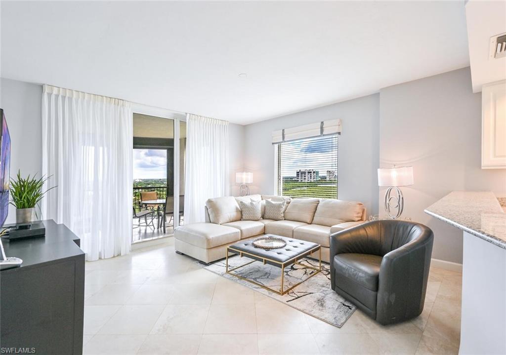 Spacious living area featuring large format tile flooring, a sliding glass door to an outdoor balcony, and a window with blinds