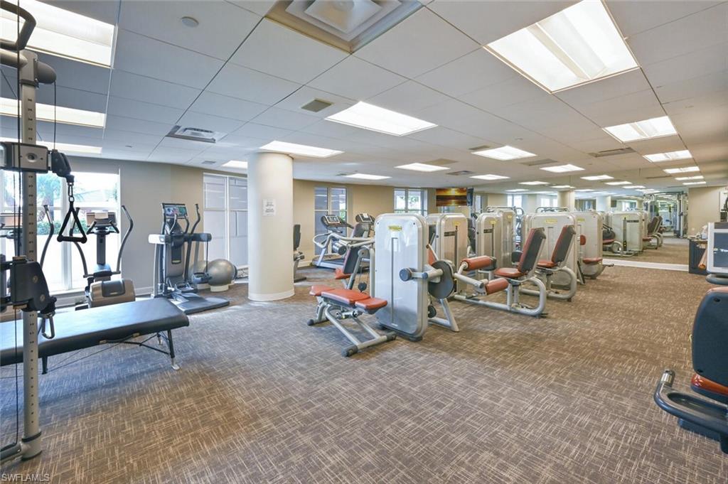 Fitness center featuring extensive mirror walls, recessed ceiling lighting, textured carpet flooring, and multiple exercise machines