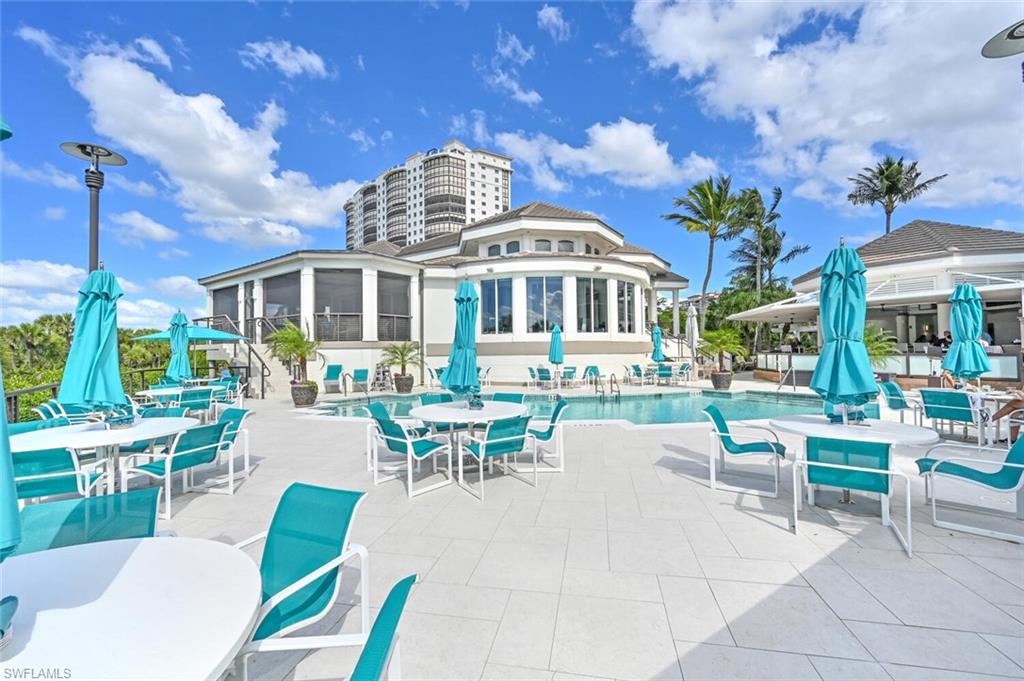 Expansive outdoor pool deck featuring a geometric swimming pool, light-toned pavers, and a resort-style building