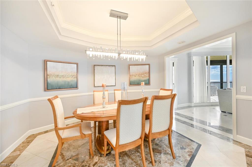 Dining area featuring a tray ceiling, contemporary chandelier, and two-tone wall molding