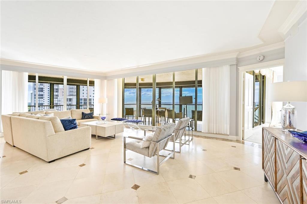 Spacious living area featuring expansive floor-to-ceiling windows, light-toned tile flooring with contrasting accents, and crown molding