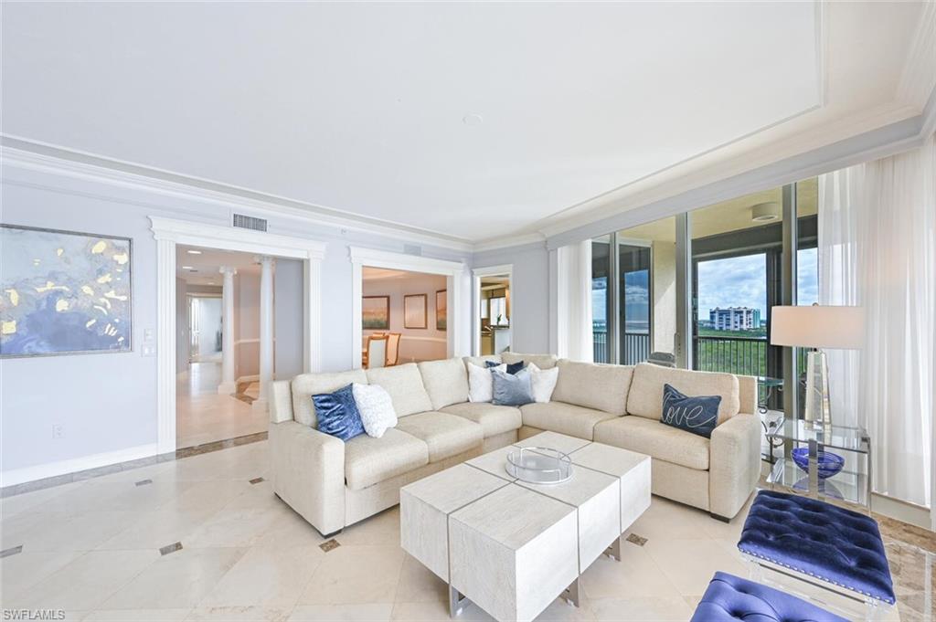 Spacious living area featuring floor-to-ceiling sliding glass doors, crown molding, and large-format tile flooring with contrasting accents