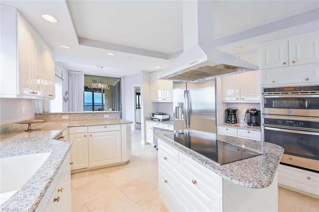 Gourmet kitchen featuring white cabinetry, light granite countertops, stainless steel appliances, a center island with a cooktop, and recessed lighting