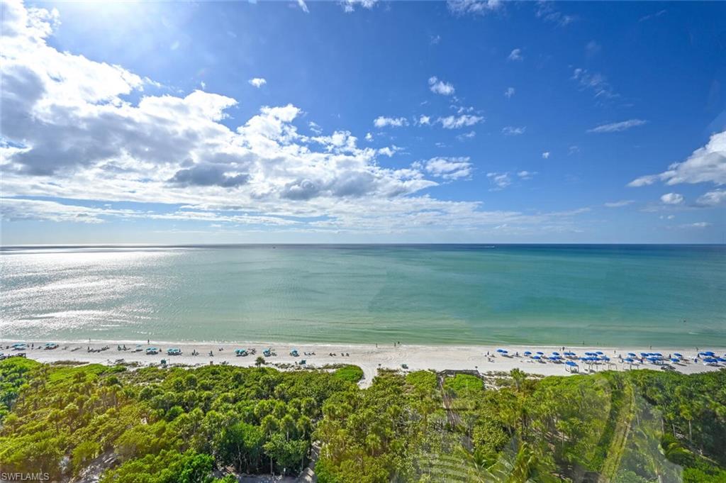 Expansive oceanfront vista featuring a white sand beach, clear turquoise waters, and lush green foliage