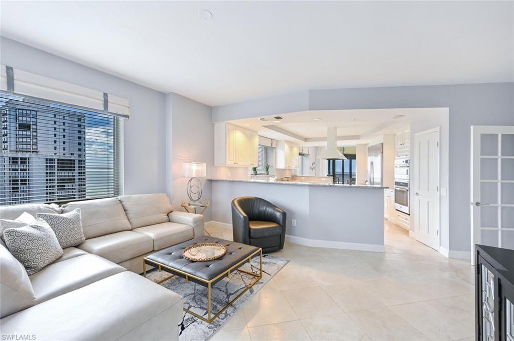 Open concept living space featuring neutral color palette, large format tile flooring, and integrated kitchen
