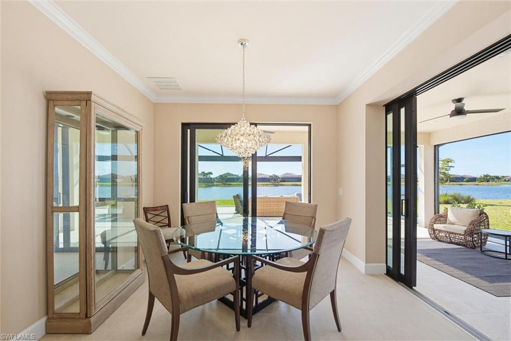 Dining space featuring hanging lights, a water view, crown molding, and a ceiling fan
