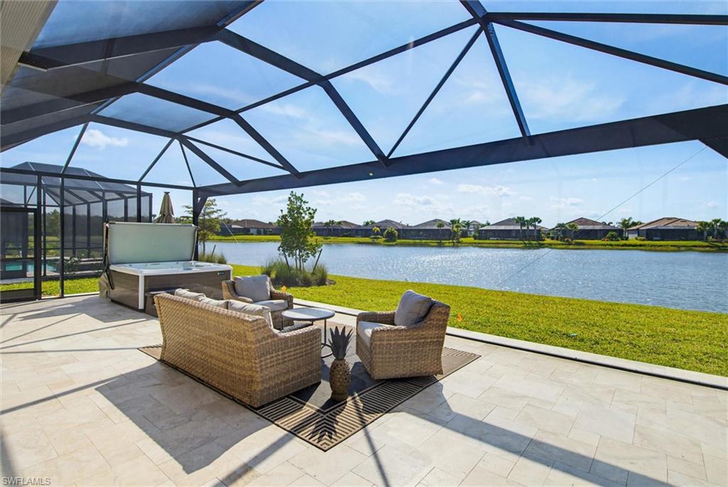 View of patio with a lanai, a sunroom, a hot tub, a residential view, and a water view