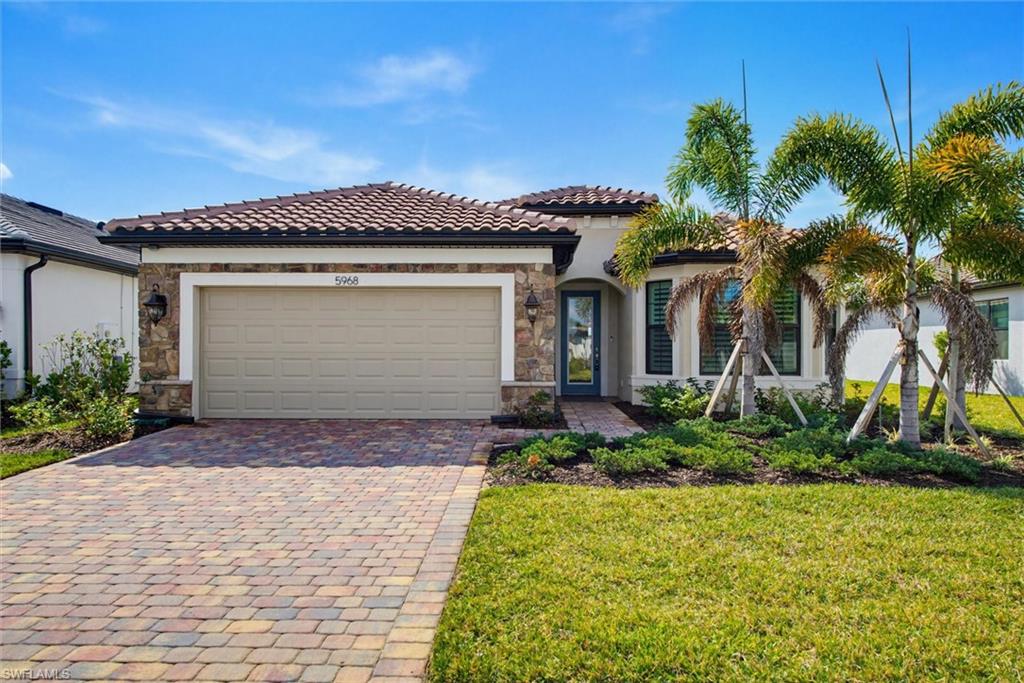 Mediterranean / spanish-style home with stone siding, an attached garage, decorative driveway, and stucco siding