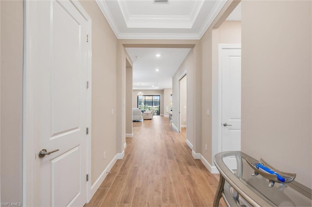 Long hallway featuring wood-finish flooring, recessed lighting, white baseboards, and neutral wall tones