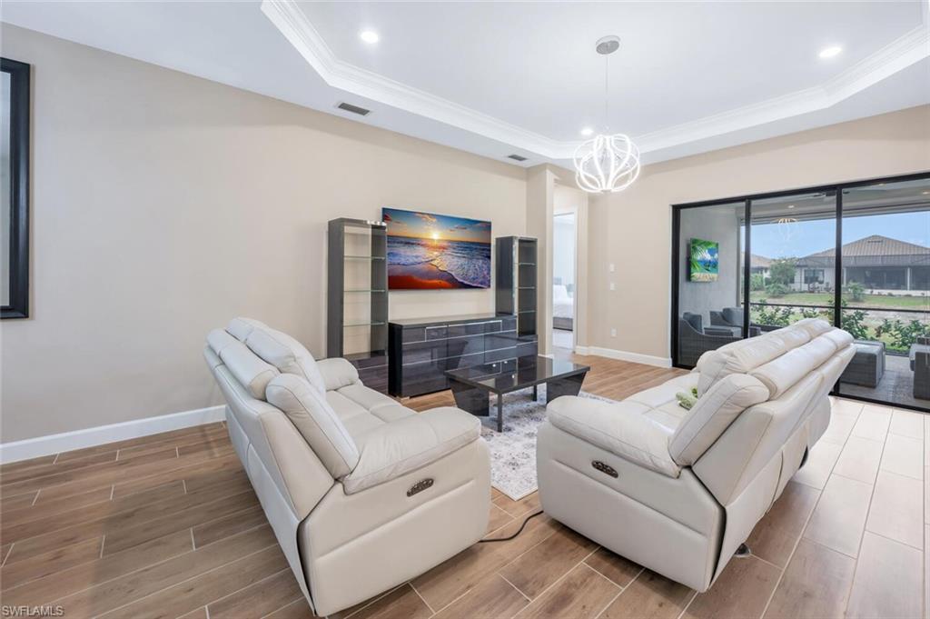 Living area featuring wood-finish flooring, crown molding, recessed lighting, and a modern pendant light fixture