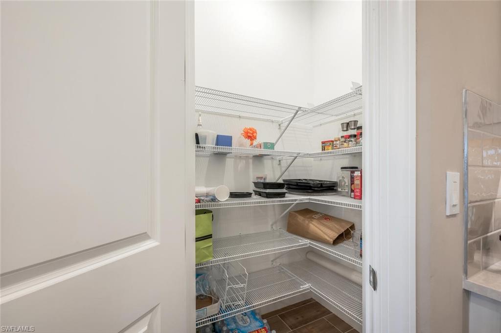 Walk-in pantry featuring wire shelving, wood-finish flooring, and ample storage capacity