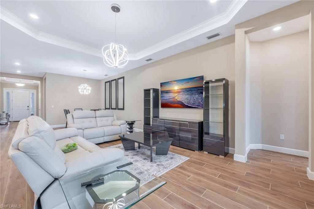 Living area featuring wood-finish flooring, recessed lighting, crown molding, and a tray ceiling