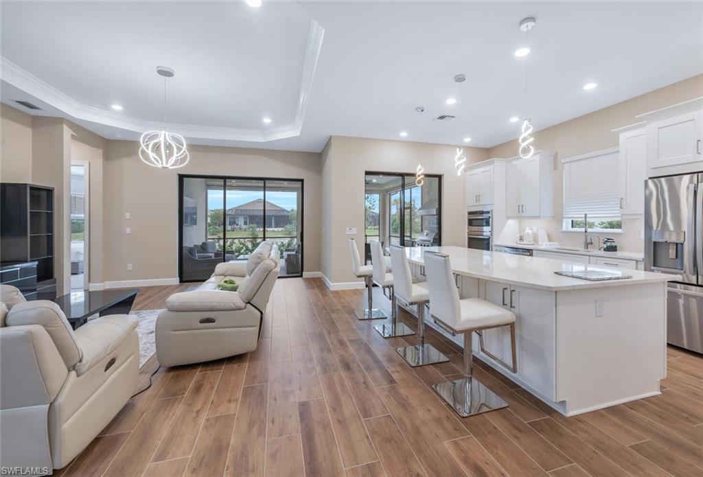 Open concept living area featuring wood-finish flooring and a tray ceiling with recessed lighting