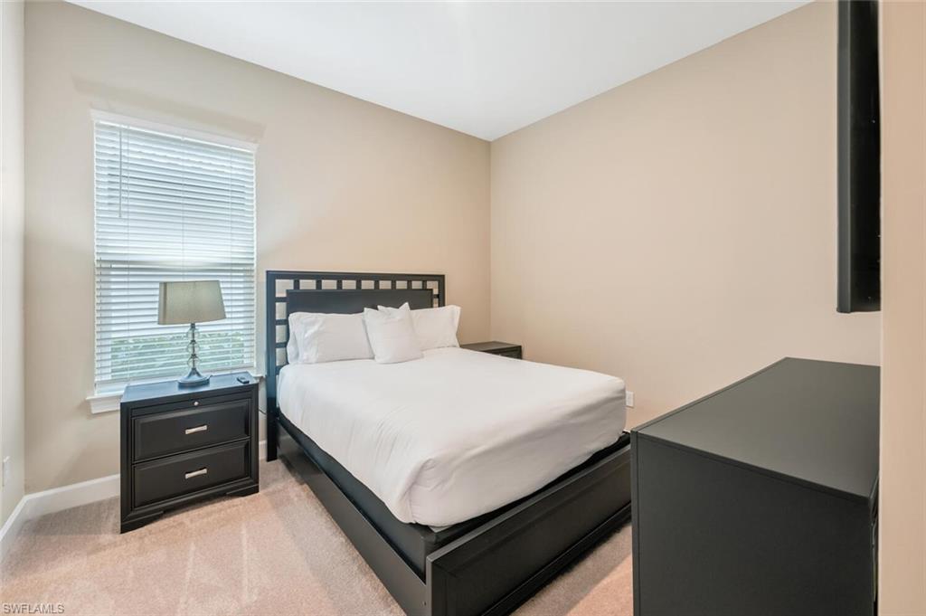 Carpeted bedroom featuring a window with blinds, light tan wall paint, and white trim