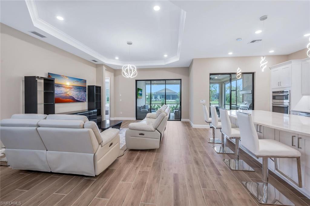 Open concept living area featuring wood-finish flooring and a tray ceiling with recessed lighting