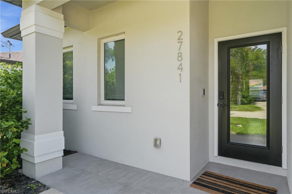 Contemporary exterior featuring smooth stucco, a full-lite entry door, and large house numbers
