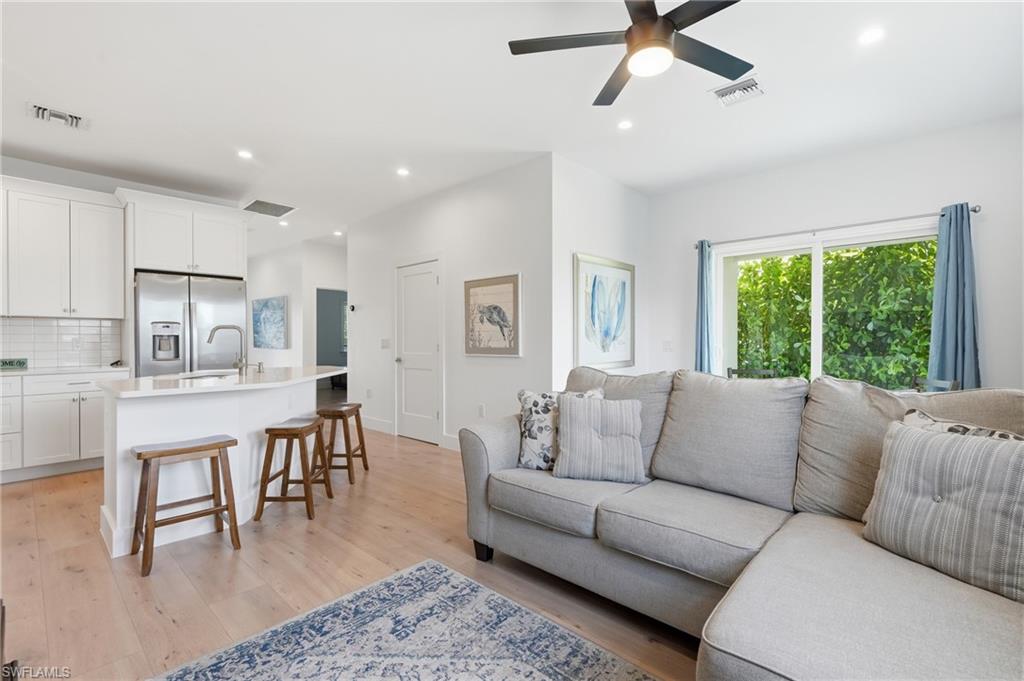 Open-concept living area with light wood-finish flooring, recessed lighting, and a contemporary ceiling fan