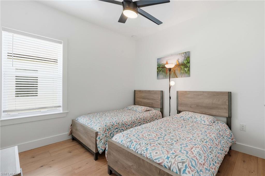 Bright room featuring wood-finish flooring, a contemporary ceiling fan, and a window with horizontal blinds