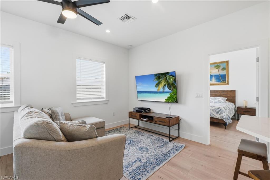 Living area featuring light wood-finish flooring, white walls, and two windows with blinds