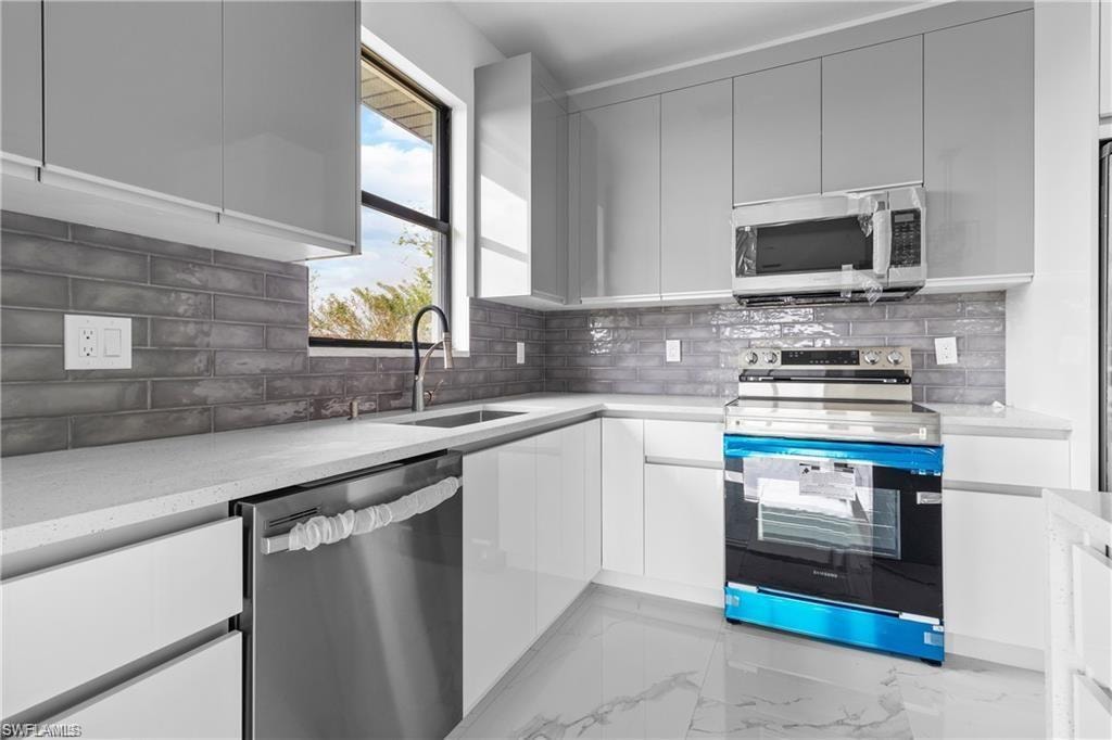 Modern kitchen featuring white cabinetry, light countertops, and a gray subway tile backsplash
