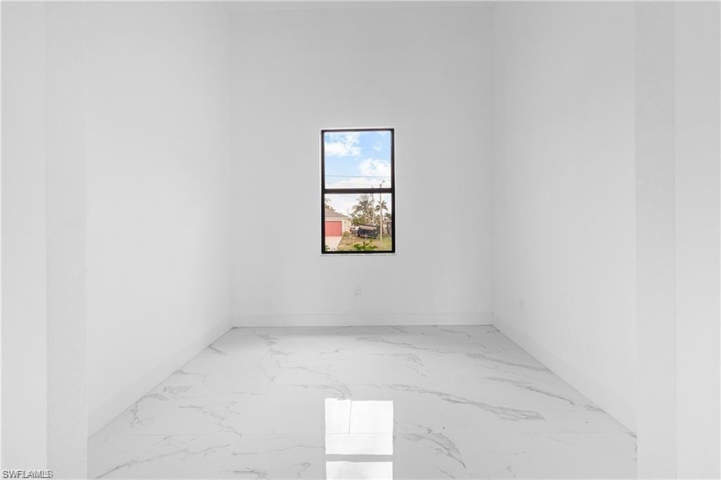 Spacious room featuring a single window, white walls, and large format tile flooring