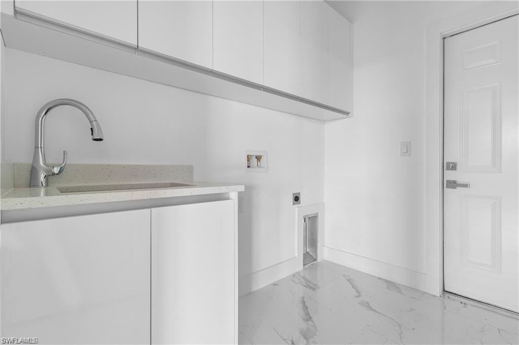 Dedicated laundry area featuring white cabinetry, a light-toned countertop, and a contemporary gooseneck faucet