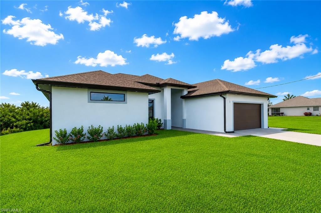 Contemporary stucco exterior with a brown shingle roof, integrated garage, concrete driveway, and established landscaping