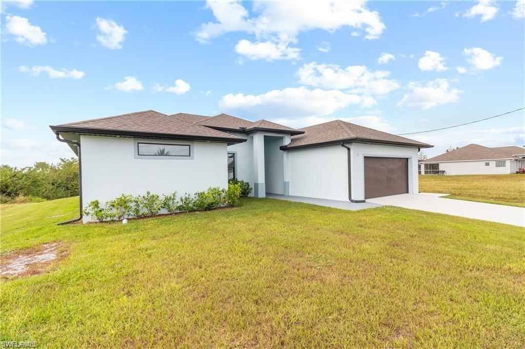 Contemporary single-story residence featuring a two-car garage, concrete driveway, white stucco exterior, and a dark shingle roof