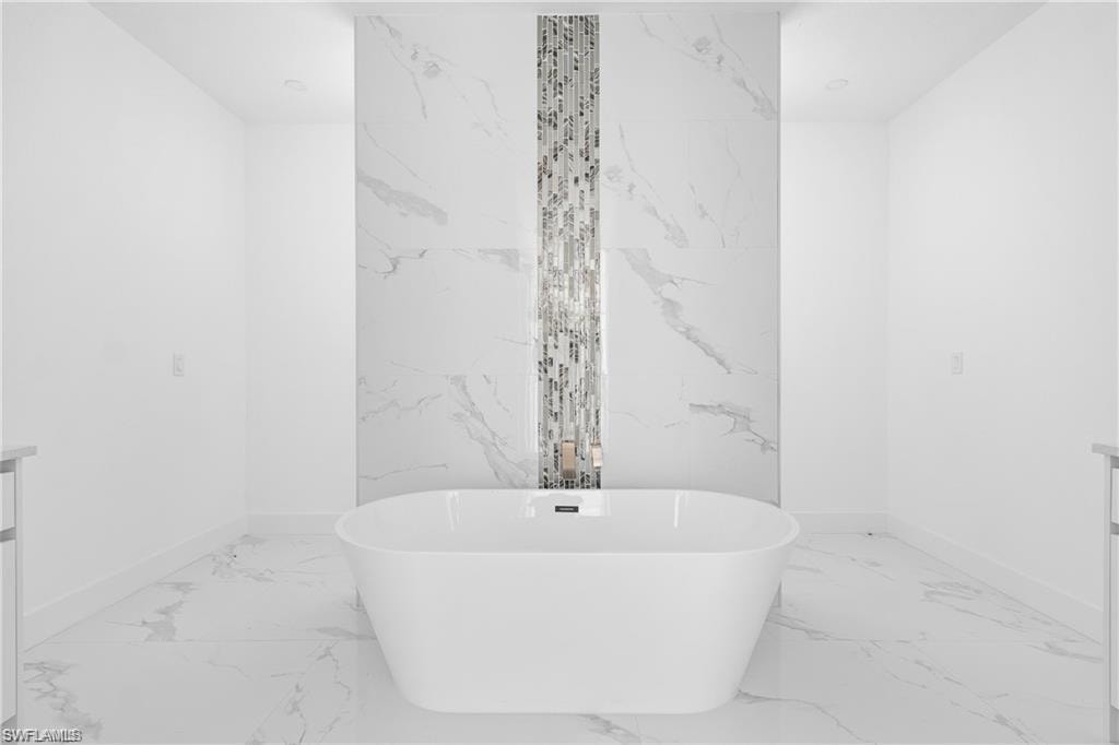Freestanding soaking tub with a floor-mounted faucet set against a feature wall