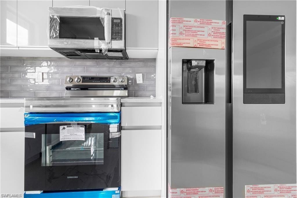 Modern kitchen featuring new stainless steel appliances, including a microwave, range, and side-by-side refrigerator