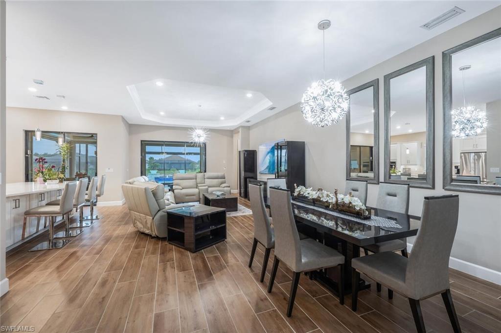Open-concept living space with wood-finish flooring, recessed lighting, and a tray ceiling