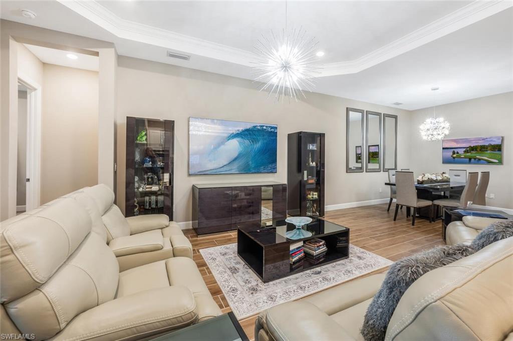 Open concept living area featuring wood-finish flooring, recessed lighting, and a tray ceiling with crown molding