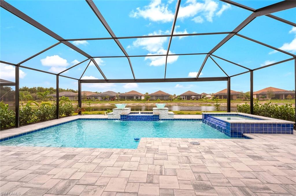 Screened lanai featuring a swimming pool, integrated spa, decorative water features, and paver decking