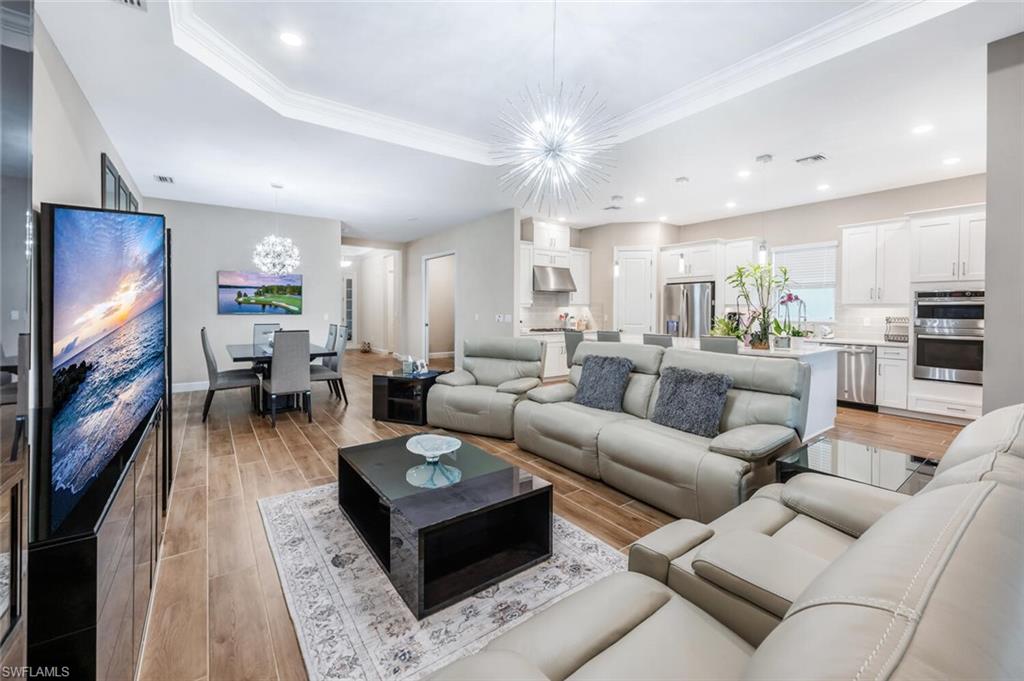 Open-concept living space with wood-finish flooring, a tray ceiling, and recessed lighting