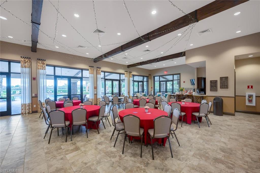 Spacious event hall featuring exposed ceiling beams, recessed lighting, and large windows with exterior access