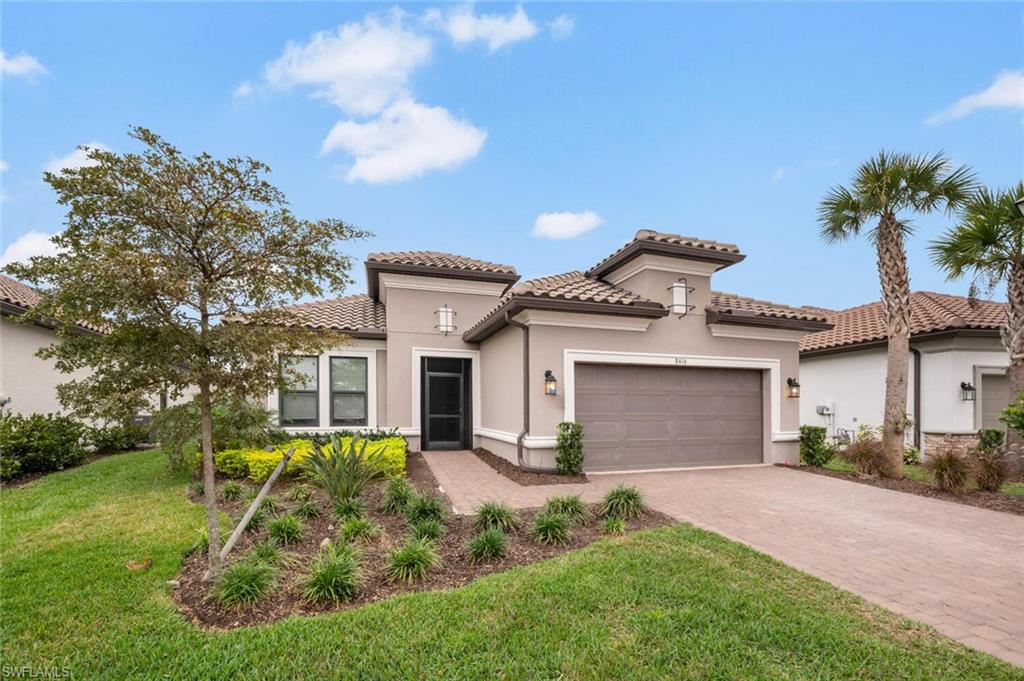Contemporary stucco exterior with a tile roof, paver driveway, and a screened front entry