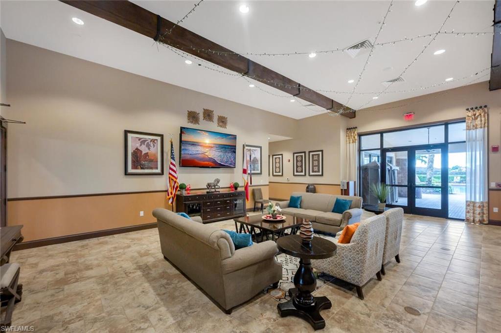 Spacious common area featuring high ceilings with exposed wood beams, recessed lighting, and large format tile flooring