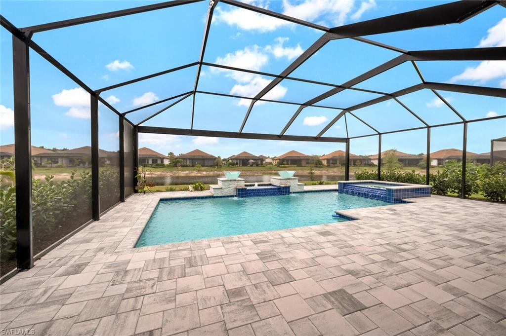 Screened outdoor living area featuring a rectangular pool and integrated spa