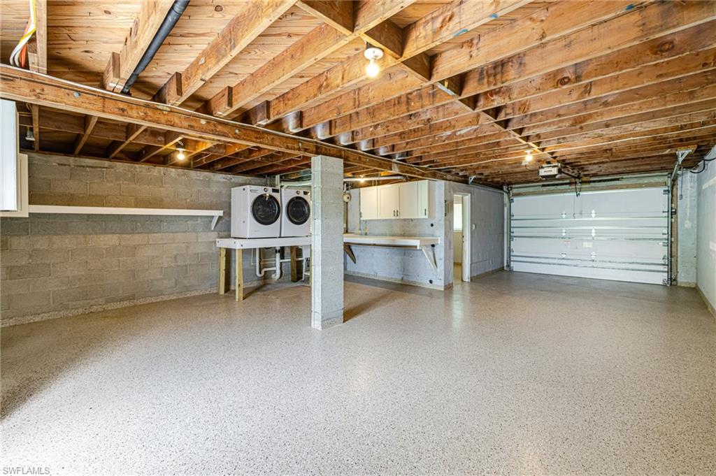 Spacious garage with exposed wood beam ceiling and light-colored speckled flooring