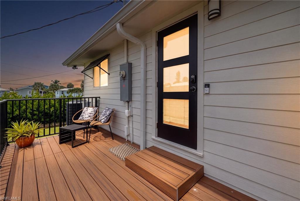 Exterior deck featuring wood-finish flooring, black metal railing, and a modern entry door with three glass inserts