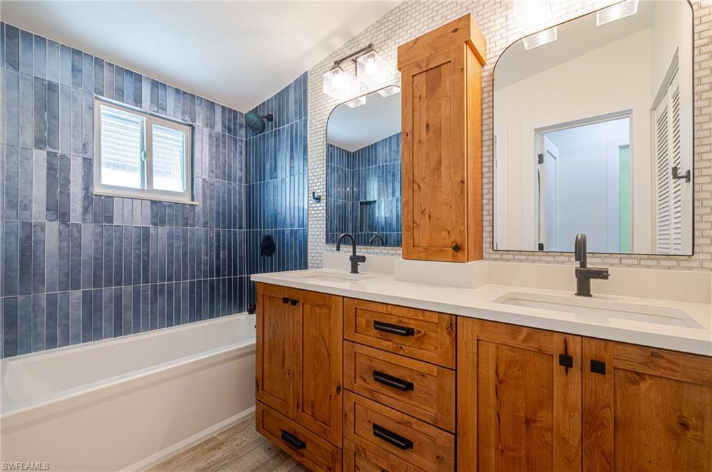 Dual wood-finish vanity with integrated sinks and white countertops, featuring matte black fixtures and hardware