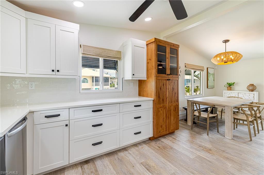 Contemporary kitchen featuring white shaker cabinetry with dark hardware, solid surface countertops, and a subway tile backsplash