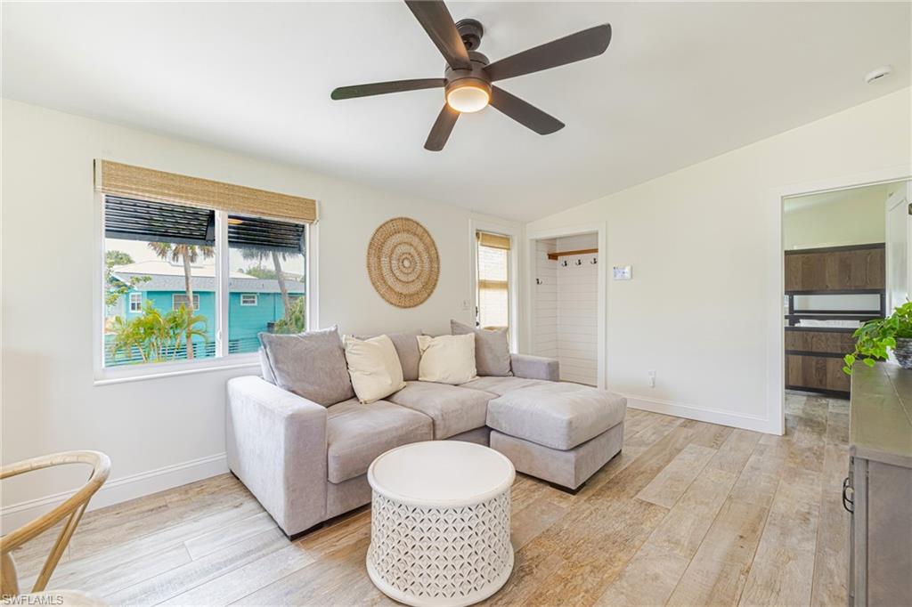 Living area featuring wood-finish flooring, a contemporary ceiling fan, and a window with woven blinds