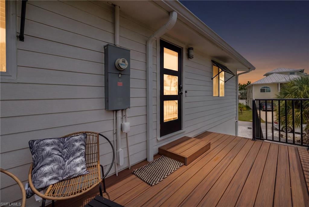 Exterior featuring horizontal plank siding, a wood-finish deck with black metal railing, a modern black entry door with multiple glass panes, and an exterior light fixture