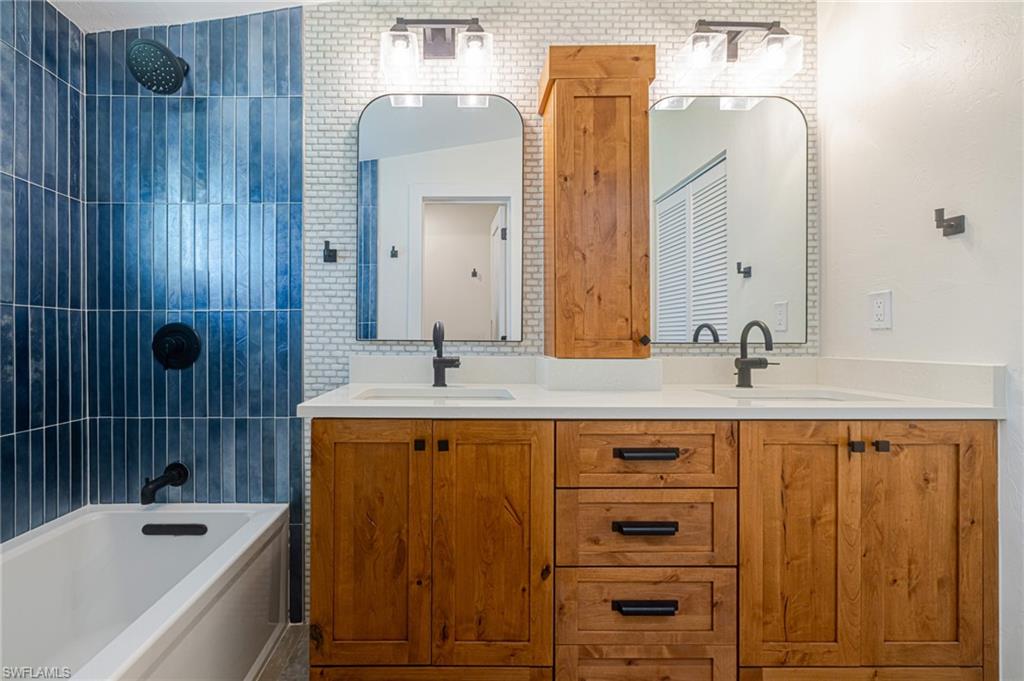 Bathroom featuring a double vanity with wood cabinetry, white countertops, and matte black fixtures