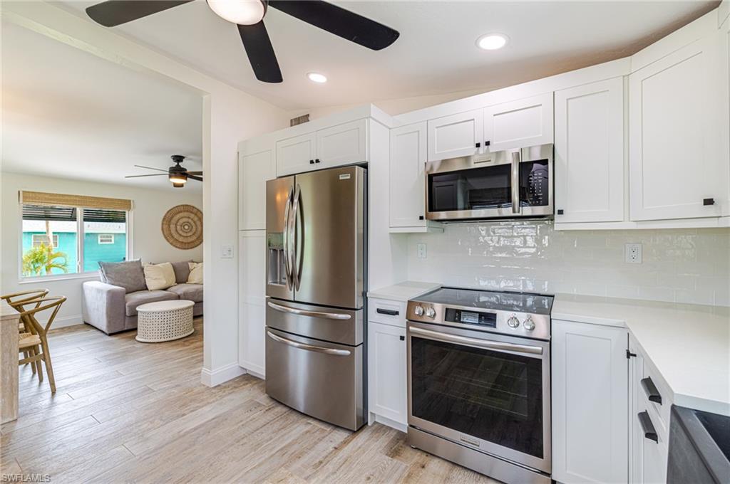 Contemporary kitchen featuring stainless steel appliances, white shaker cabinetry, white subway tile backsplash, and light-toned countertops