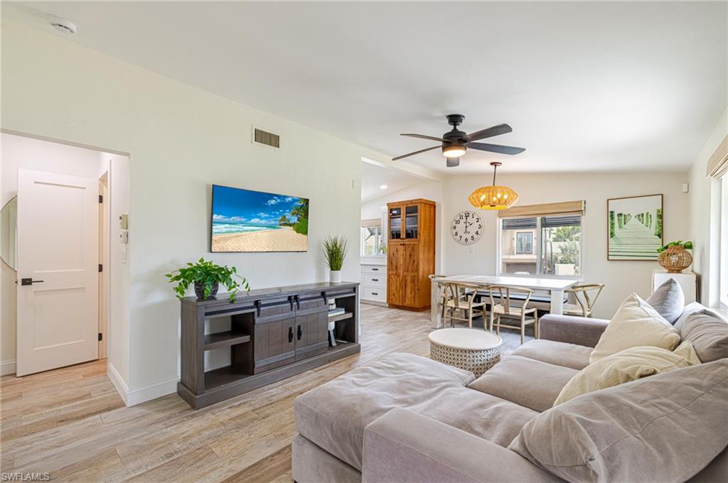 Open concept living area featuring wood-finish flooring, a ceiling fan with integrated lighting, recessed lighting, and a built-in wood-finish cabinet