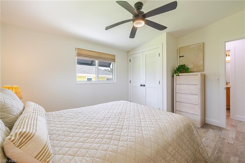 Bright room featuring a window with woven blinds, a ceiling fan with integrated lighting, louvered closet doors, and wood-finish flooring