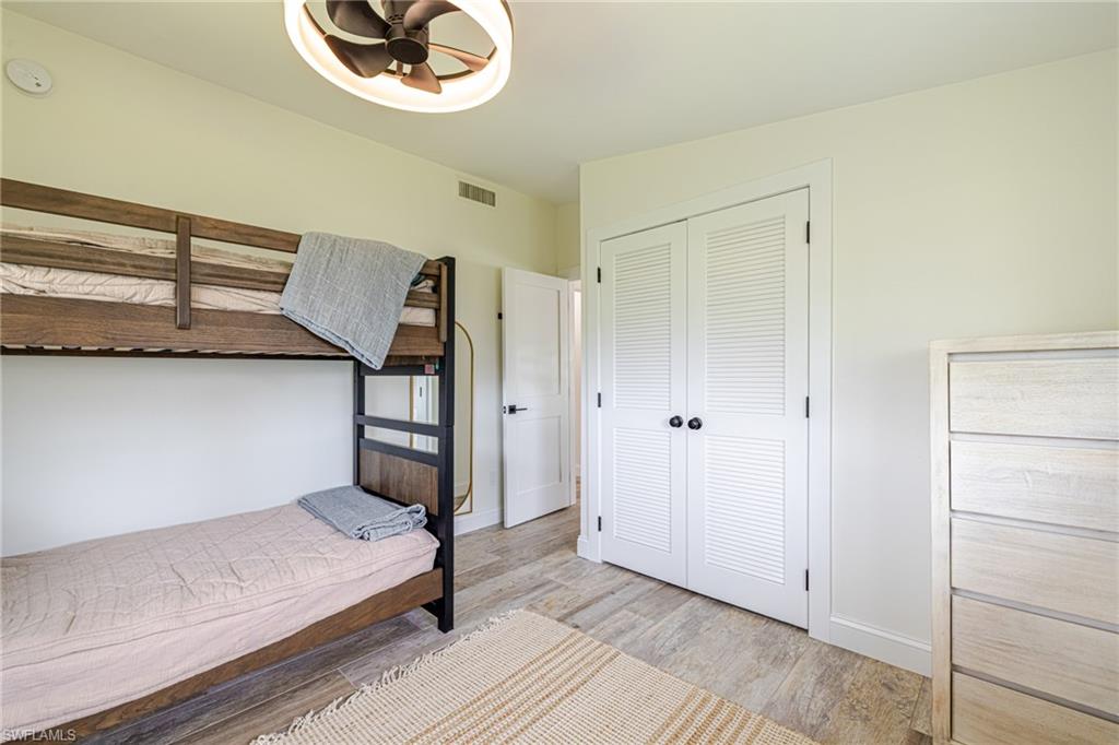 Neutral-toned bedroom featuring wood-finish flooring, a contemporary ceiling fan, and louvered bi-fold closet doors