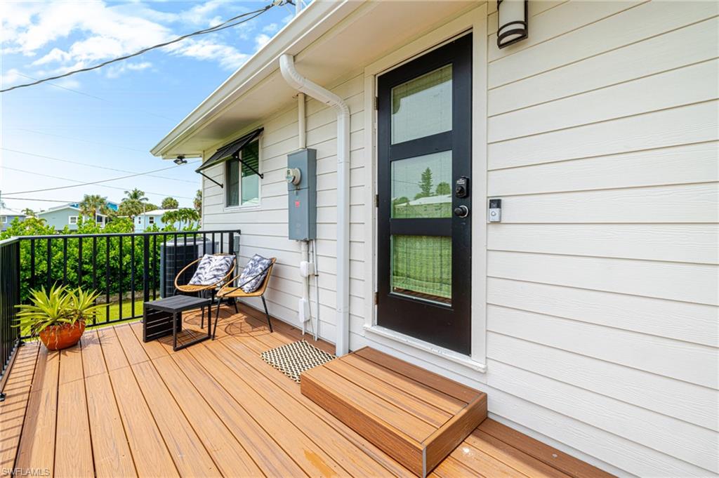 Exterior deck featuring composite wood-finish flooring, black metal railing, and white siding